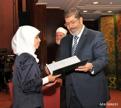 Egypt's President Mohamed Mursi, presents a prize to a youth who won the Conservation of the Holy Koran contest during the Laylat al-Qadr at Egypt Al-Azhar Conference Center at Nasr City in Cairo August 12, 2012. Egypt's...