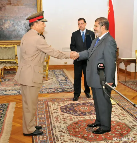 Former Armed Forces Chief of Staff Sami Anan, left, shakes hands with Egyptian President Mohammed Morsi at the Presidential Palace in Cairo, Egypt, Tuesday, Aug. 14, 2012. Egypt's president has given awards to the nation...