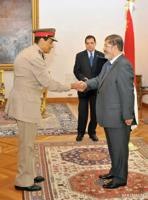 Former Defense Minister Hussein Tantawi shakes hands with Egyptian President Mohammed Morsi at the Presidential Palace in Cairo, Egypt, Tuesday, Aug. 14, 2012. Egypt's president has given awards to the nation's two top m...