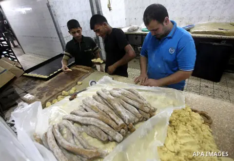 Palestinian workers make traditional date-filled cookies in preparation for the Eid al-Fitr holiday at bakery in the Gaza Strip on August 16, 2012. Muslims around the world are preparing to celebrate the Eid al-Fitr holi...