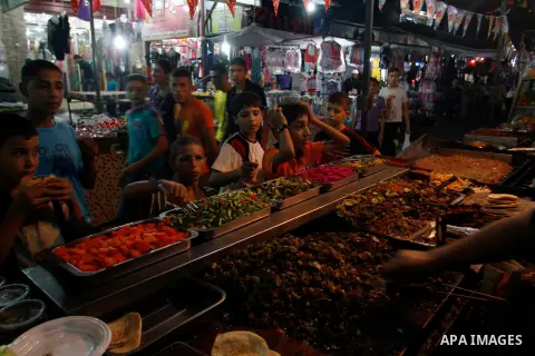 Palestinian children eat meat sandwiches at a market in the southern Gaza strip town of Rafah on Aug 16,2012, as Muslims over the world prepare to celebrate Eid al-Fitr, a three day holiday marking the end of the religio...