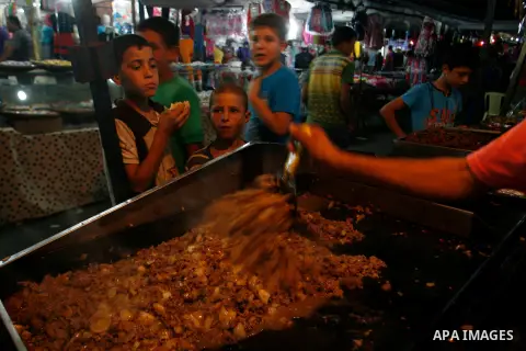 Palestinian children eat meat sandwiches at a market in the southern Gaza strip town of Rafah on Aug 16,2012, as Muslims over the world prepare to celebrate Eid al-Fitr, a three day holiday marking the end of the religio...