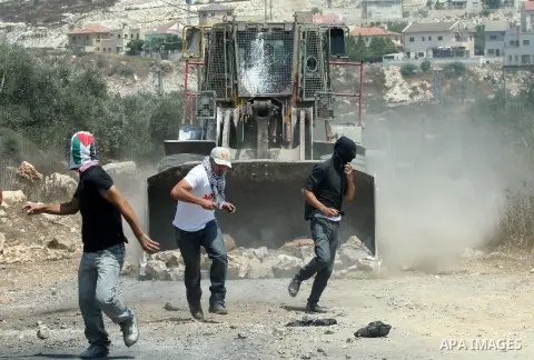 Palestinian protesters throw stones at Israeli bulldozer during a demonstration against the expropriation of Palestinian land by Israel in the village of Kfar Qaddum, near the West Bank city of Nablus, on August 17, 2012...