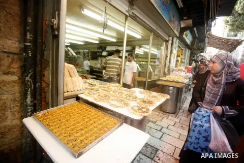 A Palestinian woman buys cake at the market during preparations for the Eid Al-Fitr feast in Jerusalem's Old City on Aug 16, 2012, as Muslims over the world prepare to celebrate Eid al-Fitr, a three day holiday marking t...