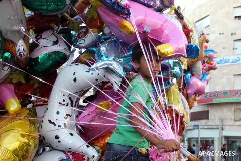 A Palestinian child sells ballons in the market during preparations for the Eid Al-Fitr feast in the West Bank city of Ramallah, on Aug 16, 2012, as Muslims over the world prepare to celebrate Eid al-Fitr, a three day ho...