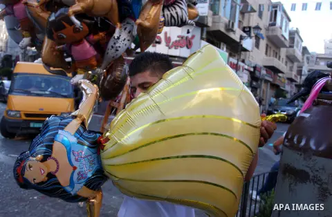 A Palestinian vendor sells ballons in the market during preparations for the Eid Al-Fitr feast in the West Bank city of Ramallah, on Aug 16, 2012, as Muslims over the world prepare to celebrate Eid al-Fitr, a three day h...