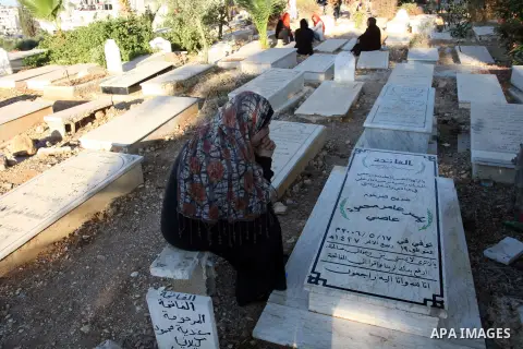 An elderly Palestinian prays next to a grave in a cemetery as part of the Eid al-Fitr traditions in the West Bank city of Ramallah, Sunday, Aug. 19, 2012. Muslims are celebrating the festival of Eid al-Fitr which marks t...