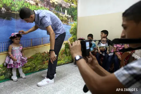 A Palestinian photographer take pictures for children in his studio in Gaza city during the first day of Eid al-Fitr which marks the end of the Muslim fasting month of Ramadan, Sunday, Aug. 19, 2012. Eid, one of the most...