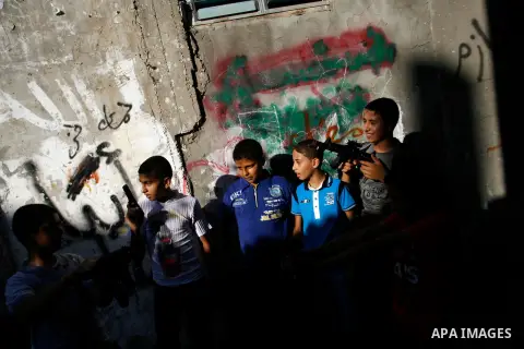 Palestinian children play with a gun toy on the Second day of Eid al-Fitr in Rafah in the southern of Gaza strip, Aug. 20, 2012. which marks the end of the Muslim fasting month of Ramadan. Eid, one of the most important...