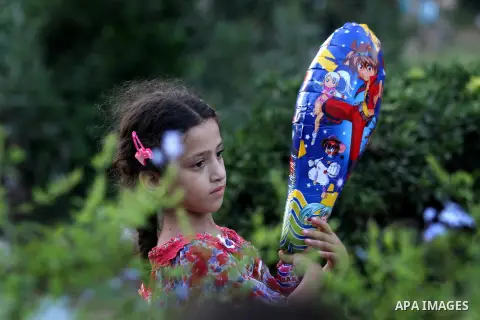 A Palestinian girl carries a ballon at a park during the Second day of Eid al-Fitr in Gaza city, Aug. 20, 2012. which marks the end of the Muslim fasting month of Ramadan. Eid, one of the most important holidays in the M...