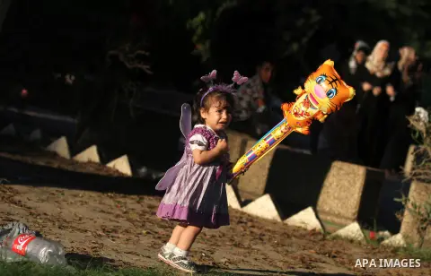 A Palestinian girl carries a ballon at a park during the Second day of Eid al-Fitr in Gaza city, Aug. 20, 2012. which marks the end of the Muslim fasting month of Ramadan. Eid, one of the most important holidays in the M...