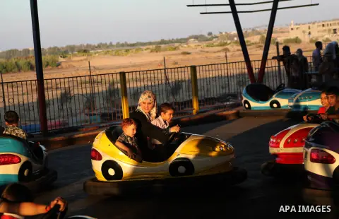Palestinians enjoy a ride in an amusement park on the third day of Eid al-Fitr, marking the end of Islam's fasting holy month of Ramadan, in Gaza City on August 21, 2012. Photo by Ashraf Amra