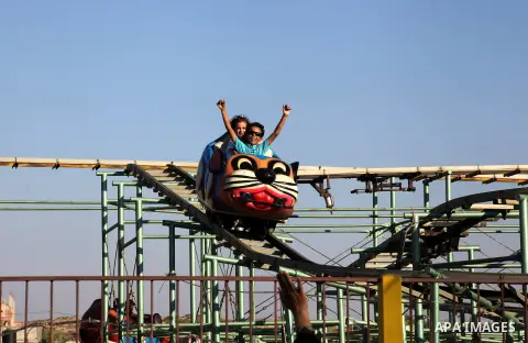 Palestinians enjoy a ride in an amusement park on the third day of Eid al-Fitr, marking the end of Islam's fasting holy month of Ramadan, in Gaza City on August 21, 2012. Photo by Ashraf Amra