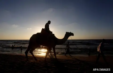 A Palestinian child ride a camel at Gaza beach during Friday holiday in Gaza city, Aug 24, 2012. Gazans escape to the beach and out from their homes during heat wave and power outages. Photo by Ashraf Amra
