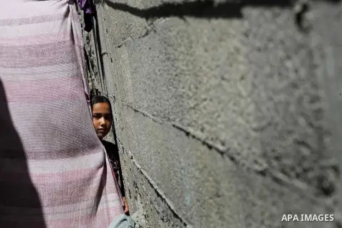 Palestinian children peer from behind a drape outside their homes at Al-Shati refugee camp in Gaza City on August 28, 2012. Life in the poor and crowded Gaza Strip is going to get harsher still unless action is taken now...