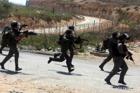 Israeli soldiers run behind Palestinian protesters outside the Ofer military prison, near the West Bank city of Ramallah, on August 28, 2012, during a demonstration in solidarity with Palestinian prisoners being held in...
