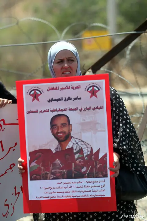 A Palestinian protester holds a sign during a demonstration in solidarity with Palestinian prisoners being held in Israeli jails, outside the Ofer military prison, near the West Bank city of Ramallah, on August 28, 2012....