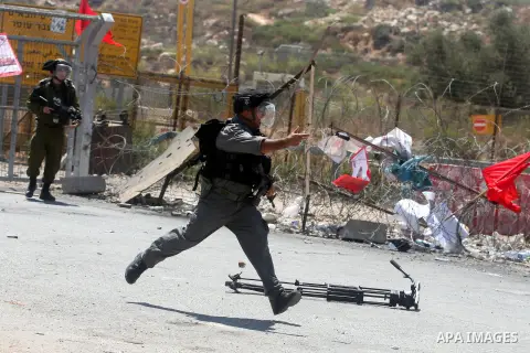 An Israeli soldier throws a tear gas canister at Palestinian protesters outside the Ofer military prison, near the West Bank city of Ramallah, on August 28, 2012, during a demonstration in solidarity with Palestinian pri...