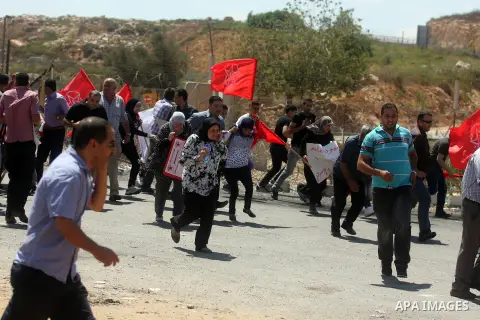 Palestinian protesters run for cover from tear gas fired by Israeli soldiers outside the Ofer military prison, near the West Bank city of Ramallah, on August 28, 2012, during a demonstration in solidarity with Palestinia...