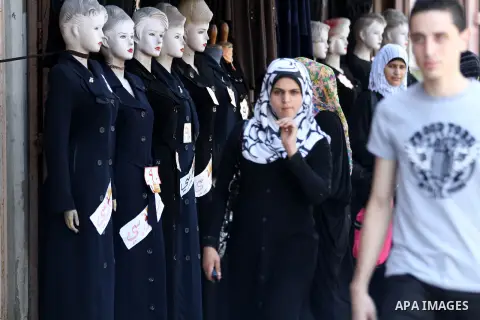 Palestinians walk past school uniforms displayed at a market in Gaza city on Aug 28, 2012. Next Sunday the First day for the new school year according to Palestinian Ministry of Education in the Gaza strip and the West B...