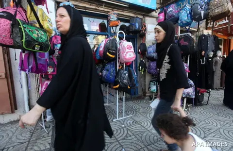 Palestinian women walk past school uniforms and bags displayed at a market in Gaza city on Aug 28, 2012. Next Sunday the First day for the new school year according to Palestinian Ministry of Education in the Gaza strip...