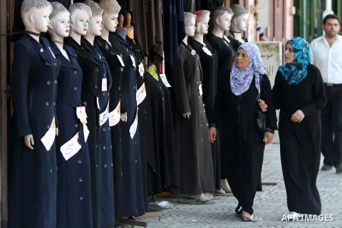 Palestinian women walk past school uniforms displayed at a market in Gaza city on Aug 28, 2012. Next Sunday the First day for the new school year according to Palestinian Ministry of Education in the Gaza strip and the W...