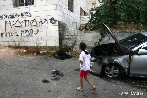 A Palestinian girl looks for Hebrew graffiti that reads "Death to Arabs" and "Migron", referring to the Jewish settlement of Migron, on the facade of a house by vandals believed to be Jewish extremists in the West Bank v...