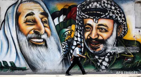 Palestinians walk in front of a mural of the Palestinian Leader Yasser Arafat in Gaza City, on Aug. 29, 2012. A French court has opened an investigation into the death of the late Palestinian leader Yasser Arafat in 2004...