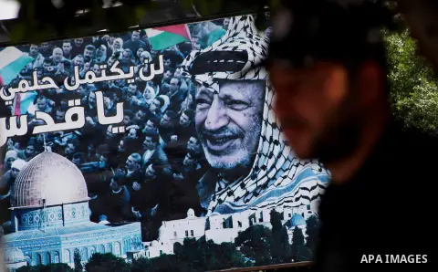 Palestinians walk in front of a mural of the Palestinian Leader Yasser Arafat in Gaza City, on Aug. 29, 2012. A French court has opened an investigation into the death of the late Palestinian leader Yasser Arafat in 2004...