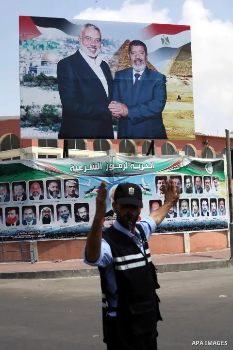 A Palestinian Hamas policeman organizes the traffic in front of a photograph released by Hamas, Egyptian President Mohammed Morsi, right, meets the Palestinian Prime Minister in Gaza, Ismail Haniyeh, in Gaza city on Aug....