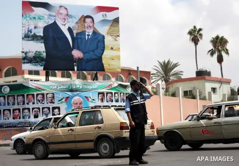 A Palestinian Hamas policeman organizes the traffic in front of a photograph released by Hamas, Egyptian President Mohammed Morsi, right, meets the Palestinian Prime Minister in Gaza, Ismail Haniyeh, in Gaza city on Aug....