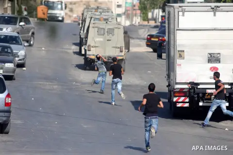 Palestinian youths throw stones at Israeli troops vehicles as they enter Om al-Sharayet neighborhood, in the West Bank city of Ramallah, Wednesday, Aug 29, 2012. Israeli soldiers raided a store in Om al-Sharayet and left...