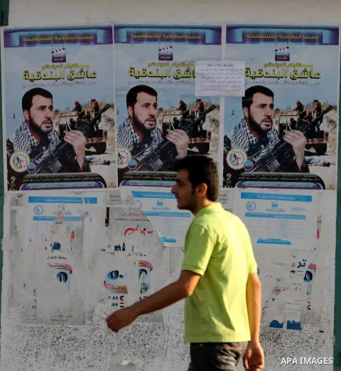 A Palestinian man walks pass a poster with a picture for cinema movie about the life of the leader in Izz al-Din al-Qassam, the military wing of hamas, the martyr Awad Silmi, in Gaza city, on Aug 28, 2012. Hamas prepare...