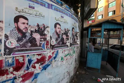 A Palestinian traffic policeman sits next to a picture for the leader in Izz al-Din al-Qassam, the military wing of hamas, the martyr Awad Silmi, on a poster invites Palestinians to view a cinema movie about his life, in...