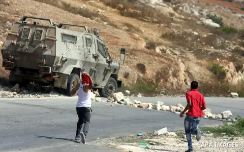 Palestinian demonstrators throws stones towards an Israeli military vehicle during a protest against the confiscation of Palestinian land to expand Jewish settlements in the West Bank village of Nabi Saleh near Ramallah...