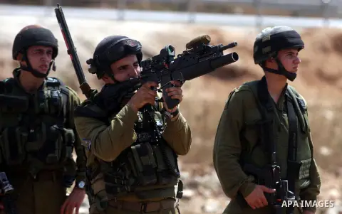 An Israeli soldier fires tear gas towards Palestinian demonstrators during clashes during a protest against the expansion of the nearby Jewish settlement of Halamish, in the West Bank village of Nabi Saleh, near Ramallah...