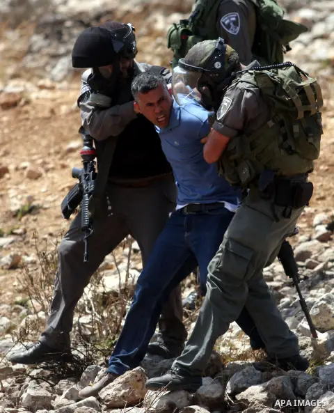 Israeli soldiers detain a demonstrator during clashes during a protest against the expansion of the nearby Jewish settlement of Halamish, in the West Bank village of Nabi Saleh, near Ramallah, Friday,August 31, 2012. Pho...