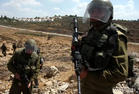 An Israeli soldier fires tear gas towards Palestinian demonstrators during clashes during a protest against the expansion of the nearby Jewish settlement of Halamish, in the West Bank village of Nabi Saleh, near Ramallah...