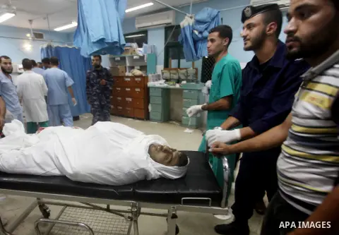 Palestinians stand by the body of one of three Palestinian militants killed in an Israeli airstrike earlier on September 5, 2012, at the morgue of the al-Aqsa hospital in Deir al-Balah, Gaza strip center. Photo by Ashraf...
