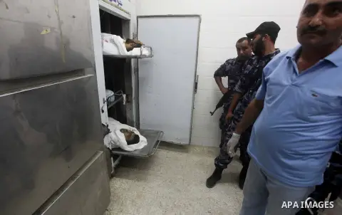 Palestinians stand by the body of one of three Palestinian militants killed in an Israeli airstrike earlier on September 5, 2012, at the morgue of the al-Aqsa hospital in Deir al-Balah, Gaza strip center. Photo by Ashraf...
