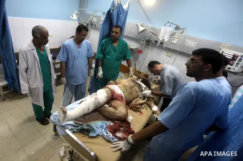 Palestinians stand by the body of one of three Palestinian militants killed in an Israeli airstrike earlier on September 5, 2012, at the morgue of the al-Aqsa hospital in Deir al-Balah, Gaza strip center. Photo by Ashraf...