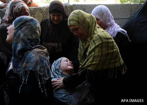 A relative of Ihab and Akram al-Zaanin, two Palestinian brothers who were killed by Israeli fire, is comforted by family members as she mourns during their funeral in Beit Hanun in the northern Gaza Strip on September 6,...