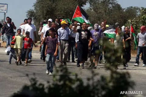 Palestinian youths wave their national flag during a protest against the confiscation of Palestinian land to expand Jewish settlements in the West Bank village of Nabi Saleh near Ramallah on Friday, Sept. 07, 2012. Photo...