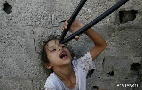 A Palestinian girl drinks water from hosepipe in front of her house in Rafah refugee camp in the southern of Gaza Strip, on September 08. 2012. Photo by Eyad Al Baba