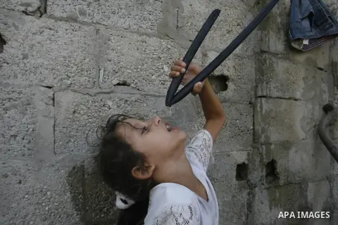 A Palestinian girl drinks water from hosepipe in front of her house in Rafah refugee camp in the southern of Gaza Strip, on September 08. 2012. Photo by Eyad Al Baba