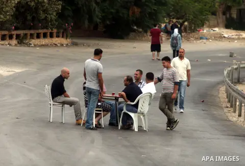 Palestinian men sit around a table as they block a street in the West Bank city of Ramallah during a protest against the high cost of living on September 10, 2012. Cities across the West Bank ground to a halt as transpor...