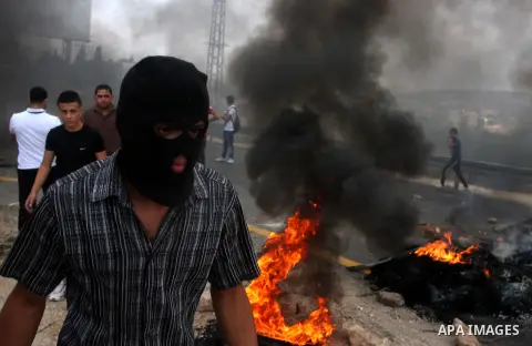 Palestinian youths close streets in Ramallah by burning tires during a protest against the high cost of living on September 10, 2012. Cities across the West Bank ground to a halt as transport unions called a mass general...