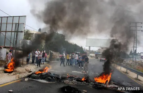 Palestinian youths close streets in Ramallah by burning tires during a protest against the high cost of living on September 10, 2012. Cities across the West Bank ground to a halt as transport unions called a mass general...