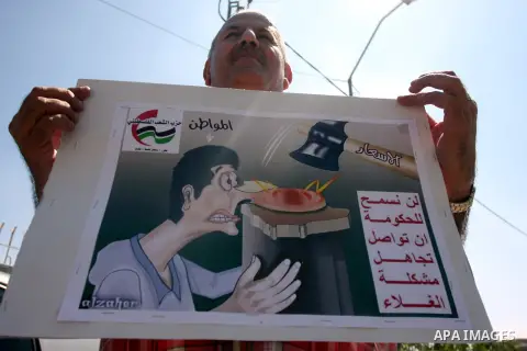 A Palestinian man hold a comics portrait during a demonstration against the high cost of living in the West Bank city of Ramallah, Sept. 11, 2012. The prime minister pledged on Tuesday that the Palestinian Authority will...