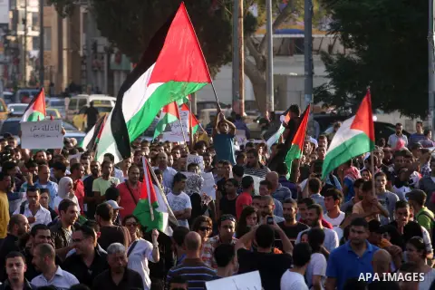 Palestinians wave their national flag during a protest against the Paris Protocol and the Oslo Agreement, both key accords which govern economic ties between Palestinians and Israelis, in the West Bank city of Ramallah o...